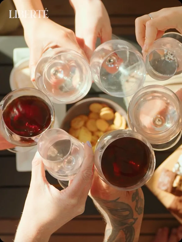 Friends raising glasses together aboard Liberté, on a private yacht charter from Auckland