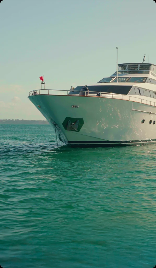 The bow of Liberté on turquoise water, on a private yacht charter from Auckland